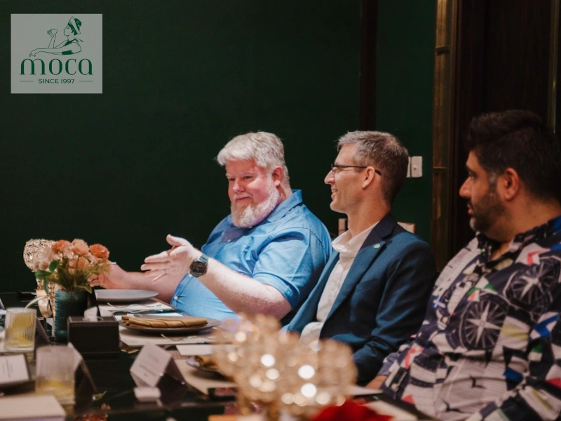 A server discreetly consults with guests to ensure a smooth and professional business lunch experience.